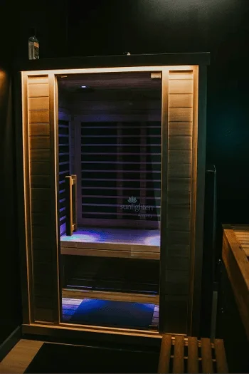 A healthcare sauna with a glass door, Amplify logo, and blue lights.