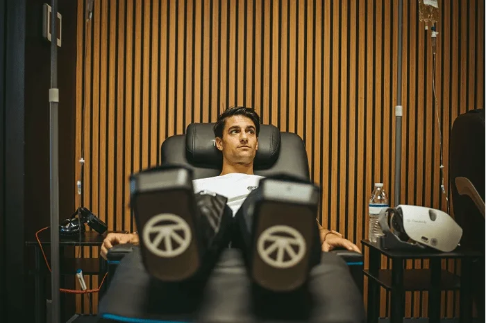 Man relaxes in a healthcare clinic with compression boots and an IV drip.