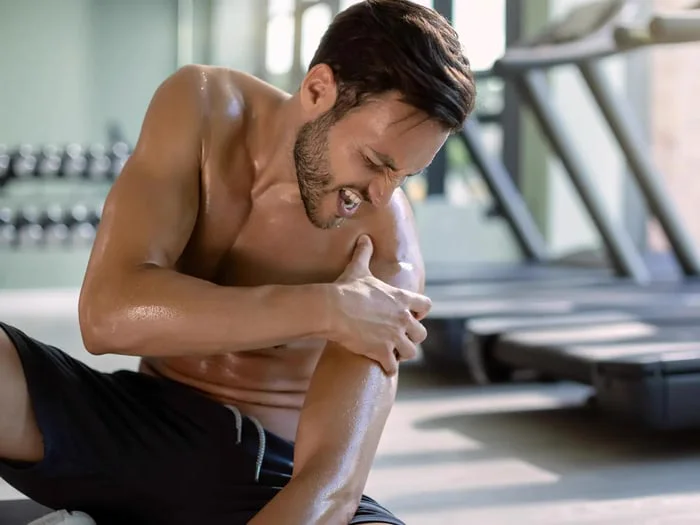 A sweating man in a gym faces slow injury recovery for his shoulder.