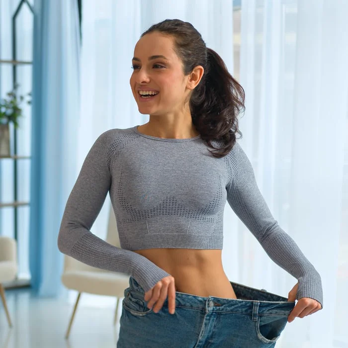 Woman proudly displays medical weight loss success in oversized jeans