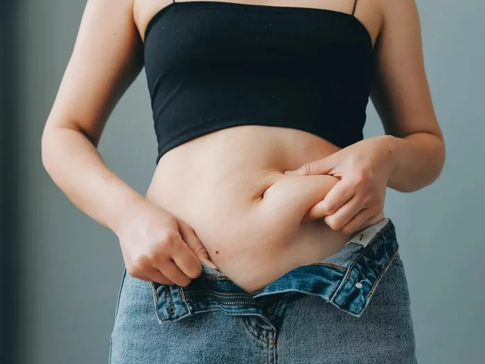 A woman wearing a crop top fights weight loss resistance.