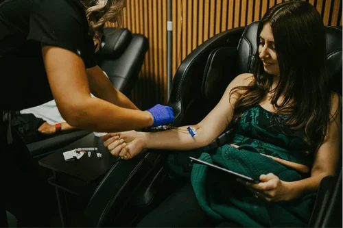 Healthcare professional inserting an IV into a young woman's arm