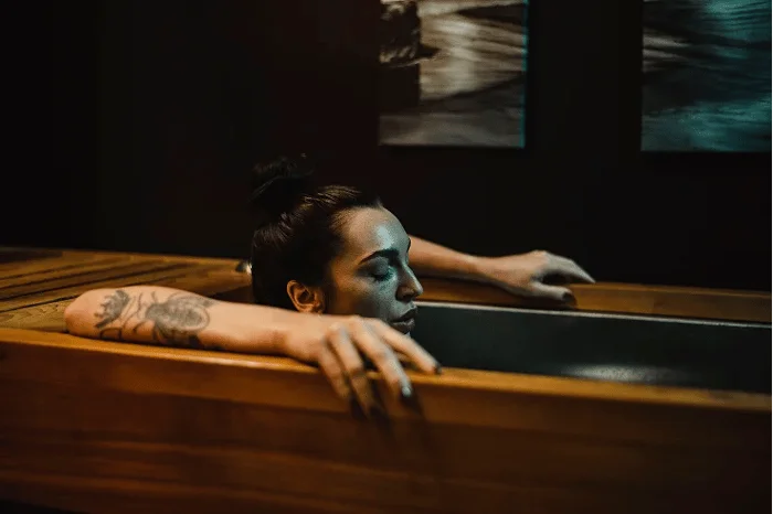 A woman relaxes in an ice bath, promoting her healthcare.