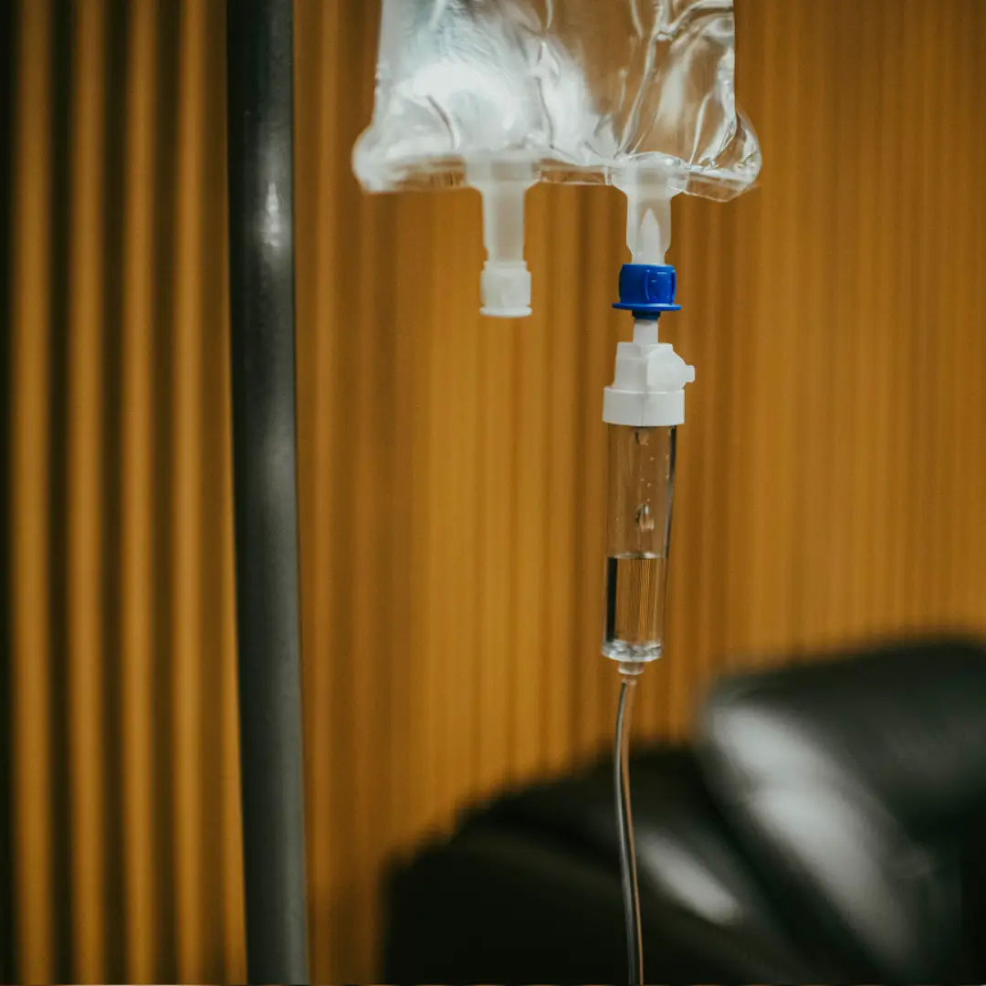 IV drip bag with clear fluid and tubing, hanging from a metal pole